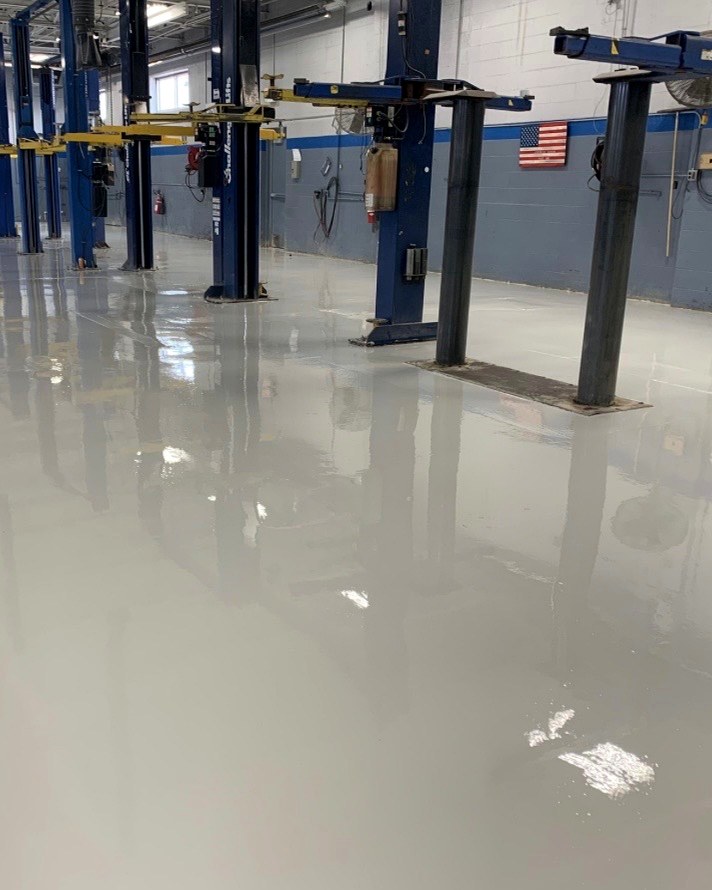 High-gloss gray epoxy floor through a commercial auto shop with vehicle lifts