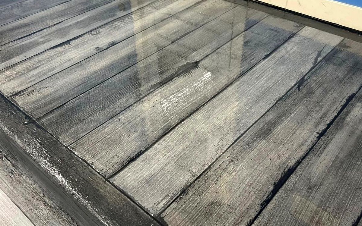 Real CrossBuilt job: gray wood-plank textured overlay coating on a covered porch